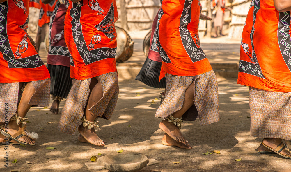 Traditional African dancers on sandals dance outdoors in brightly colored clothing