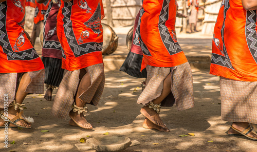 Traditional African dancers on sandals dance outdoors in brightly colored clothing