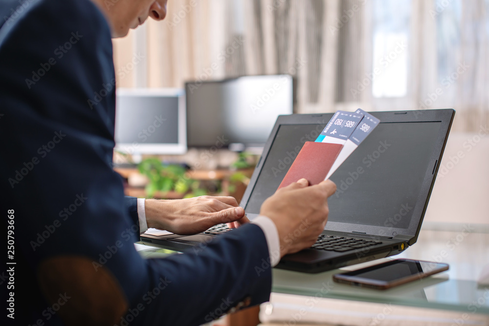 Man holding airline ticket and passport buying on the Internet using a laptop. Purchasing and booking tickets online Man holding airline ticket and passport buying on the Internet using a laptop. Purchasing and booking tickets online