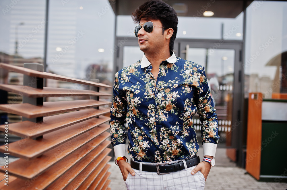 Attractive and handsome stylish indian man wear on shirt and sunglasses standing in the terrace of modern lounge cafe at his work break. Attractive and handsome stylish indian man wear on shirt and sunglasses standing in the terrace of modern lounge cafe at his work break.