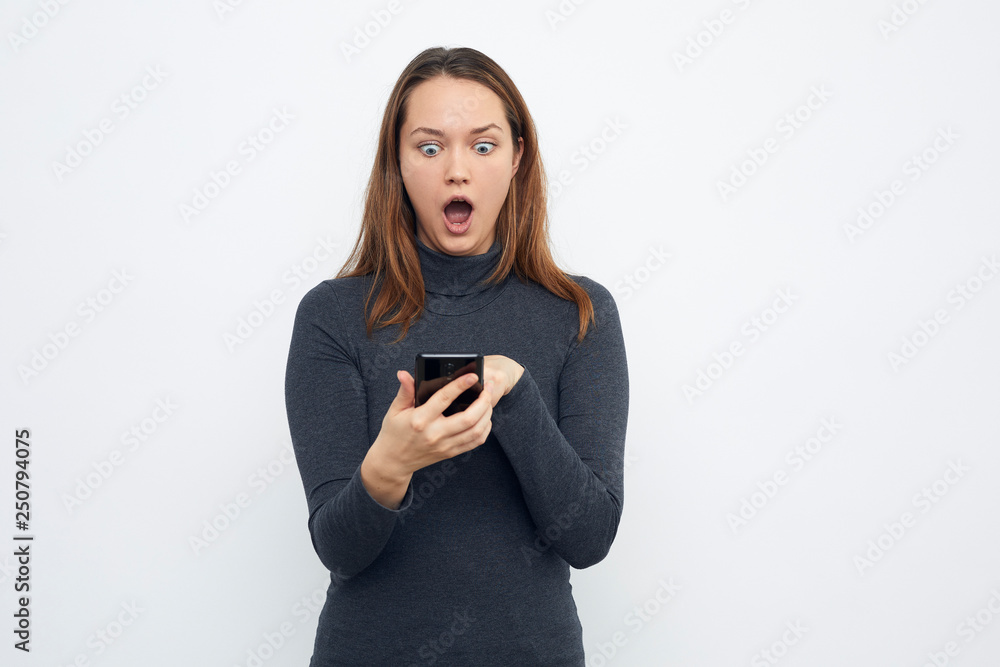 young girl using cellphone looking surprised at cellphone young girl using cellphone looking surprised at cellphone