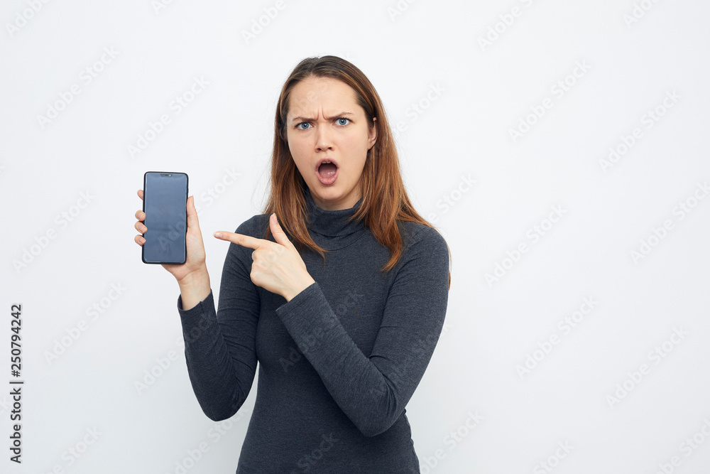 portrait of angry young woman pointing at mobile phone portrait of angry young woman pointing at mobile phone