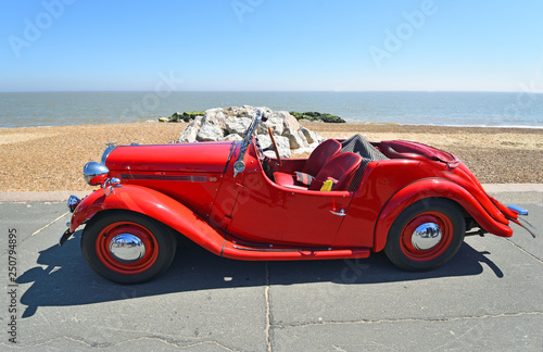 Classic Red Singer Motor Car Parked on Seafront Promenade.