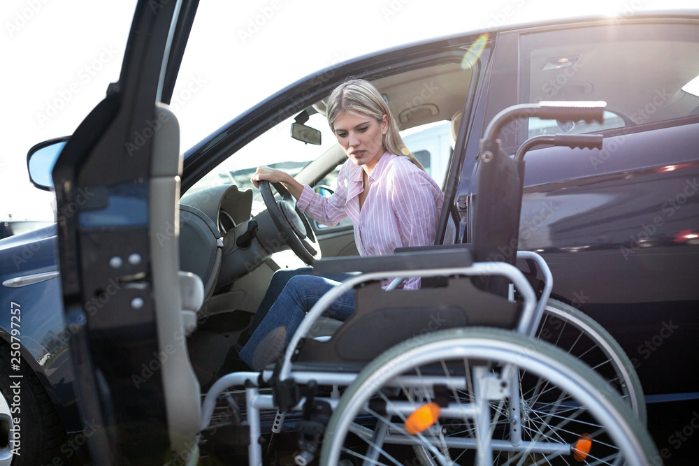 Disabled young woman preparing to switch position from driver’s seat to her wheelchair