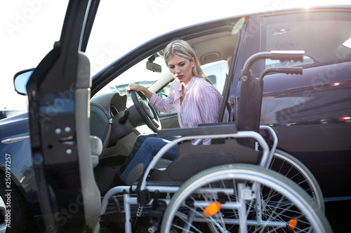 Disabled young woman preparing to switch position from driver’s seat to her wheelchair