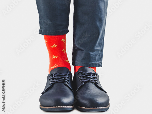Men's legs, trendy shoes, blue pants and bright socks on a white, isolated background. Close-up. Concept of style and elegance