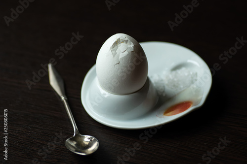 broken boiled egg with spoon, stand and salt