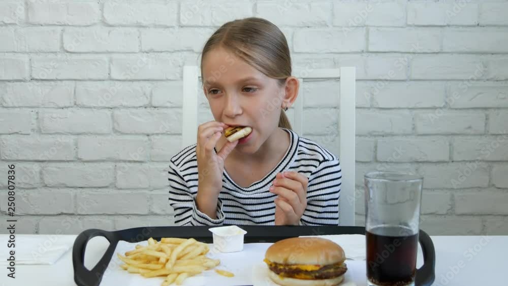 Child Eating Fast Food, Kid Eats Hamburger in Restaurant, Girl Drinking Juice Child Eating Fast Food, Kid Eats Hamburger in Restaurant, Girl Drinking Juice
