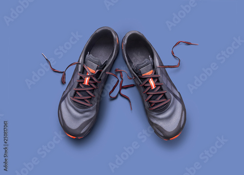 Top view of gray and orange trainers isolated on a blue background.