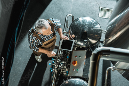 Foto overhead view of male senior brewer using digital tablet in brewery