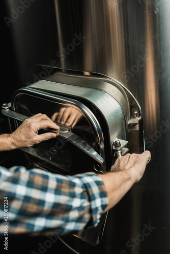 cropped view of male brewer working with brewery equipment