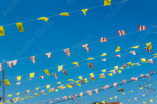 Festival flags with blue sky background at Wangkrod old market, a charming alley flanked by rickety old wooden houses lined with street vendors selling all sorts of local treats and sweets, Thailand. photo