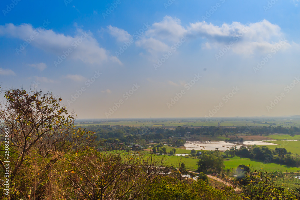 Aerial view from hilltop around with countryside green rice fields and blue sky background at Wat Khao Rup Chang or Temple of the Elephant Hill ,Phichit province, Thailand.