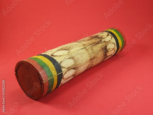 Close-up of a “ganzá”, a Brazilian rattle used as a percussion instrument, especially in samba music. It is handmade, colorful and made of bamboo. Pink background.