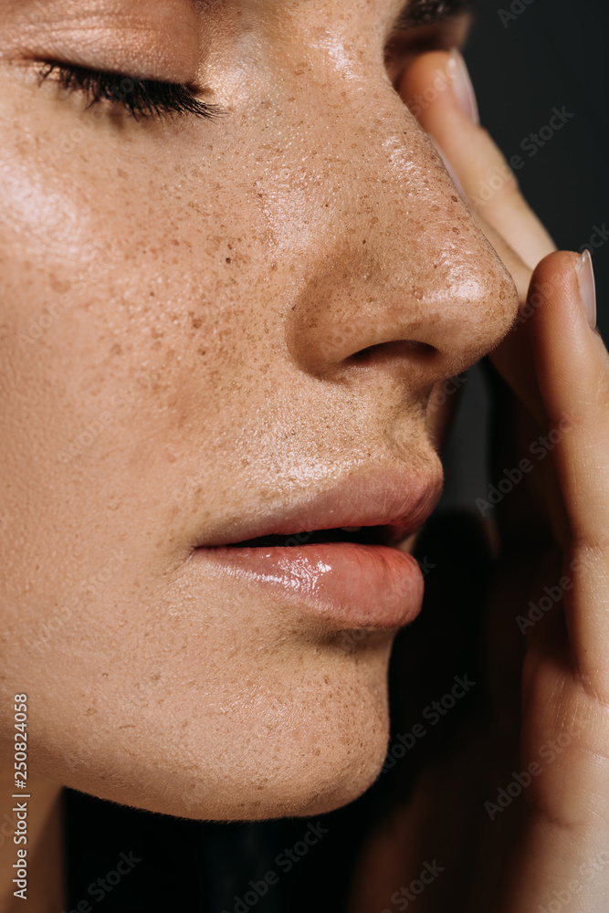 close up view of tender woman with freckles on face isolated on grey