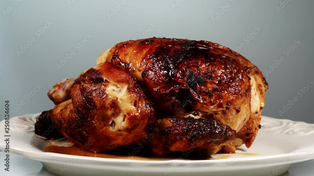 Baked roasted whole chicken with crispy skin on plate rotating Baked roasted whole chicken with crispy skin on plate rotating