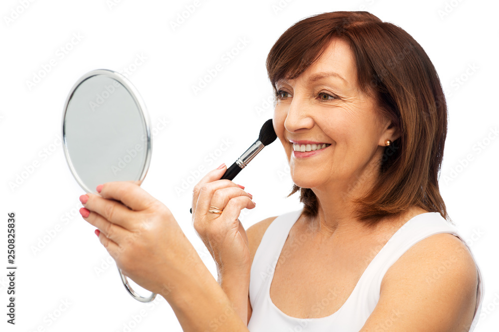 beauty, make up and old people concept - smiling senior woman with mirror applying blush by brush over white background beauty, make up and old people concept - smiling senior woman with mirror applying blush by brush over white background