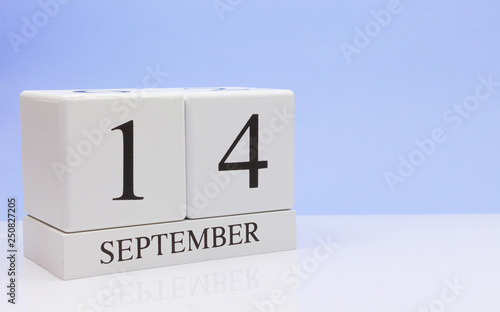September 14st. Day 14 of month, daily calendar on white table with reflection, with light blue background. Autumn time, empty space for text
