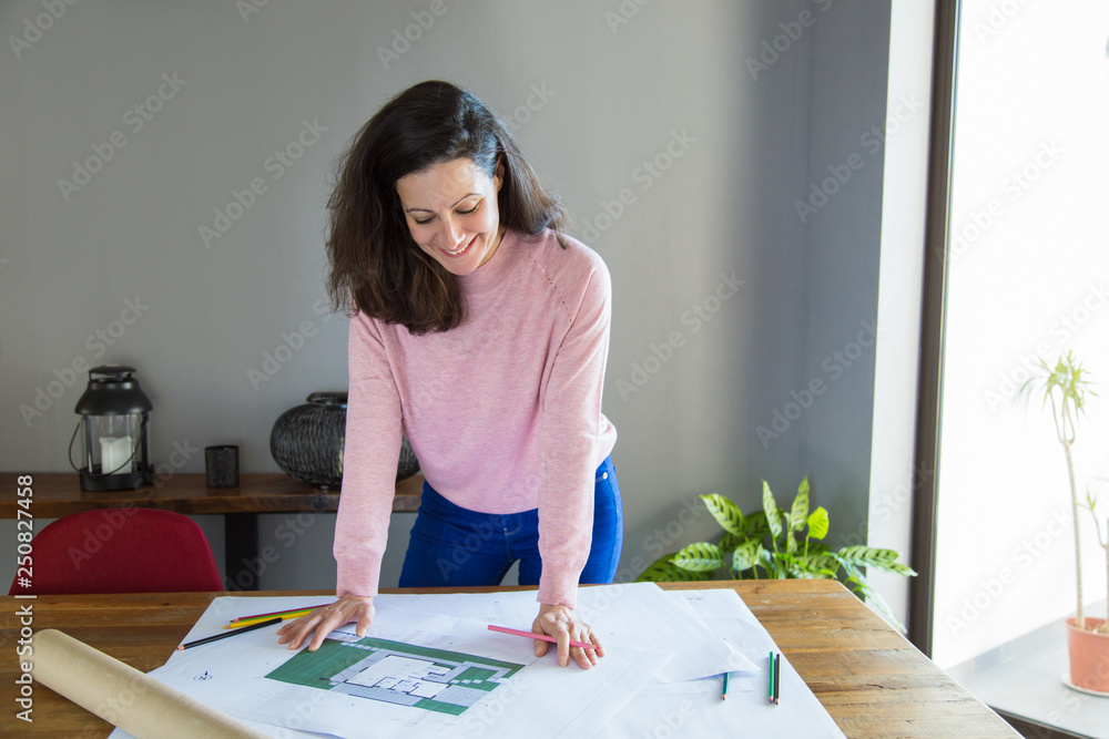Positive successful apartment designer working with floor plan