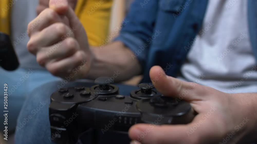 Two teenage boys playing fast paced video games, winning and clenching fists Two teenage boys playing fast paced video games, winning and clenching fists