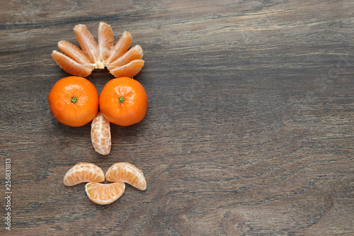 composition of peeled and unpeeled mandarins in the form of a stylized face with a smile on the background of a wooden board   with copy space