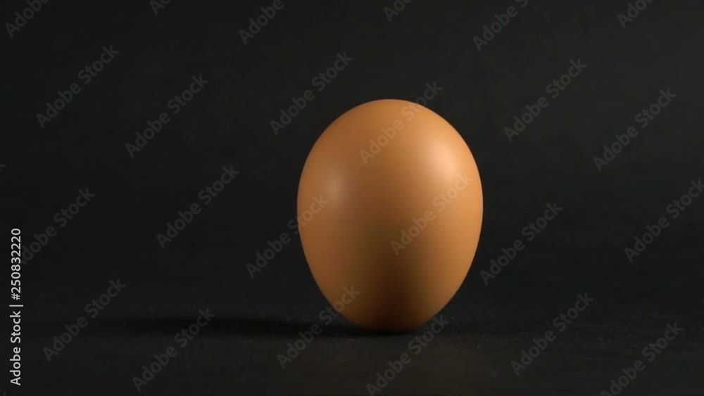 The egg spin by hand slow motion. A brown egg spinning on a black table. Showy easter background. Close up. The egg spin by hand slow motion. A brown egg spinning on a black table. Showy easter background. Close up.