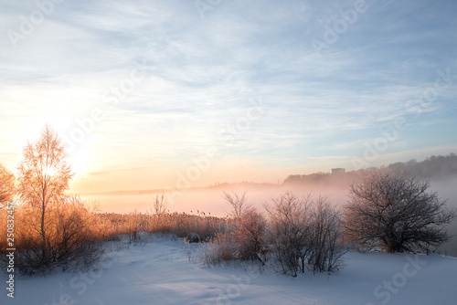 wonderful winter scene. Frosty, misty morning on the small river. frost covered trees in the warm glow of sunrise on the beach. The beauty of the world © Zelma