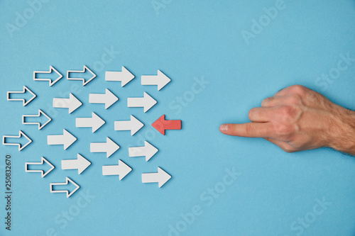 cropped view of man pointing with finger to red horizontal pointer opposite white arrows on blue background