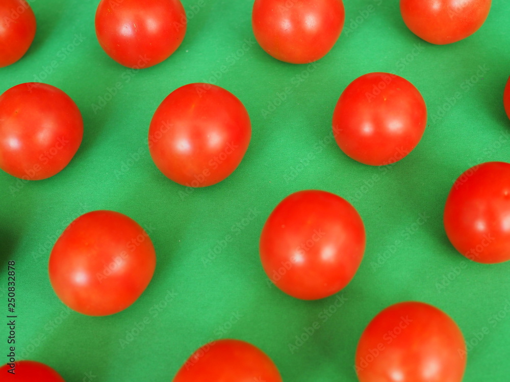 Obraz premium several bright red cherry tomatoes on a green background