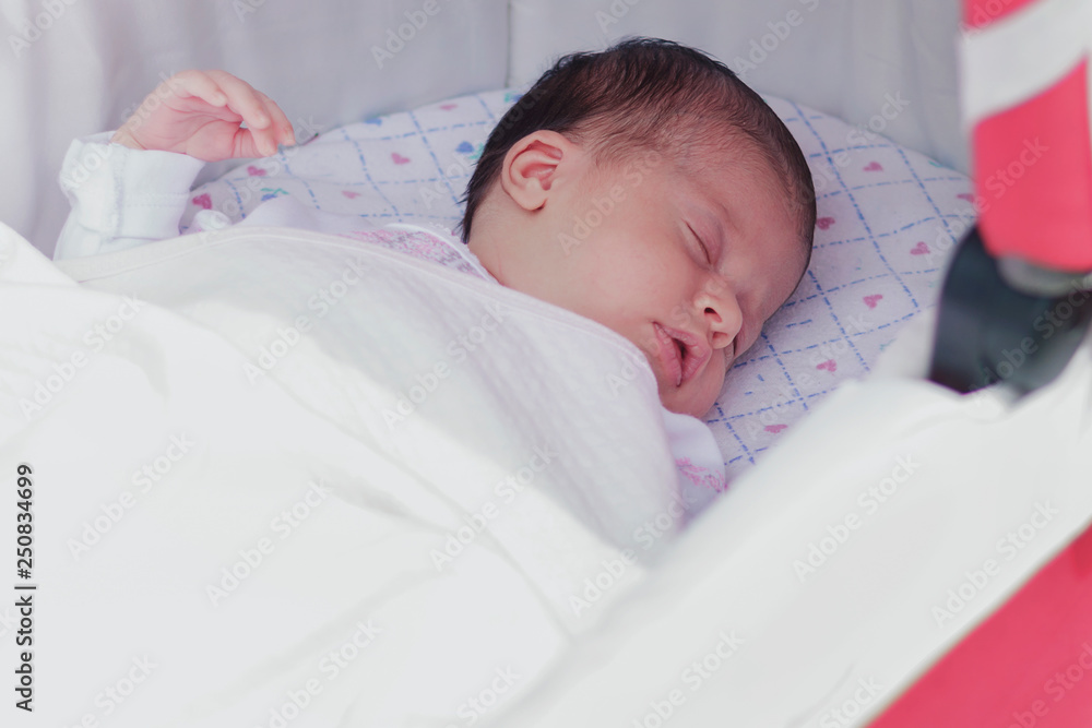 Newborn girl sleeping in the cradle opening his mouth, open air, portrait