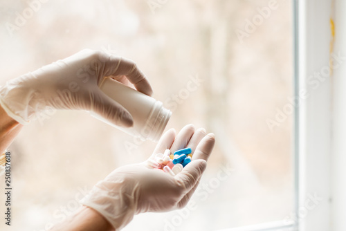 Hands in medical gloves holding different capsules