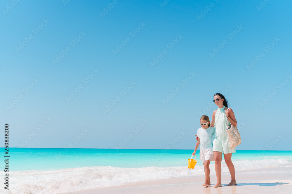 Little adorable girl and young mother at tropical beach