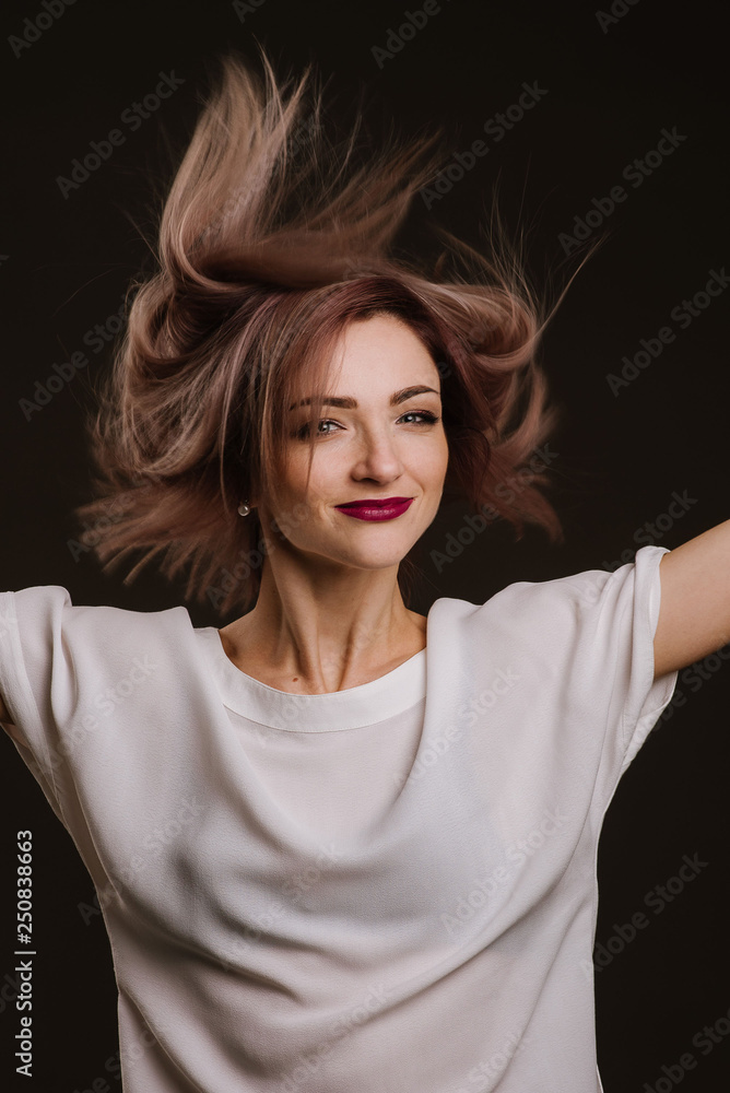 Pretty young woman posing holding her hair by the hands in studio Pretty young woman posing holding her hair by the hands in studio