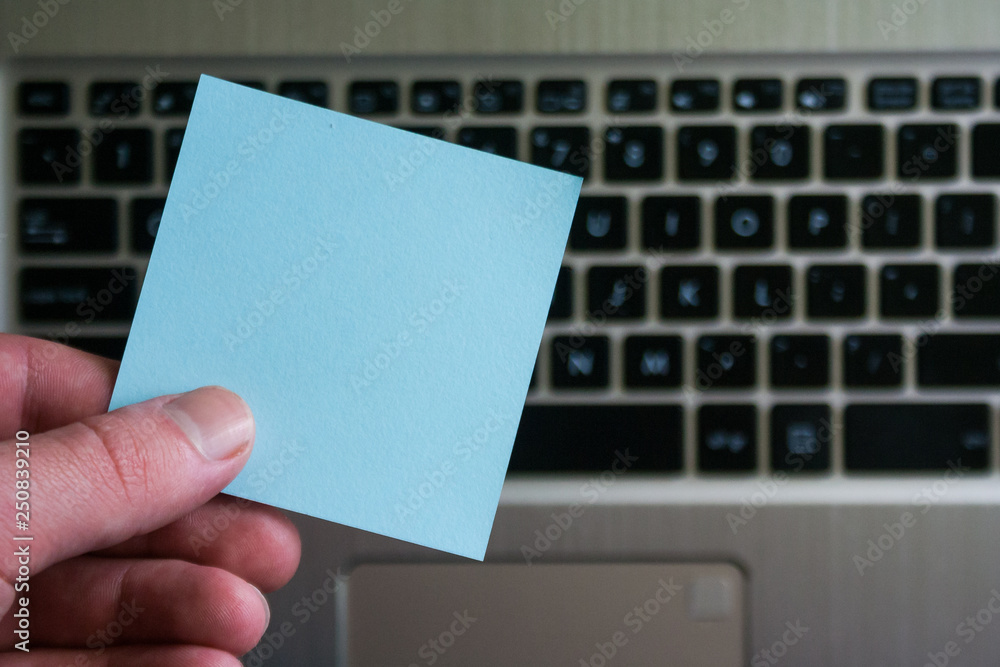 Empty sticky note on laptop keyboard background. Sticky blank in human hand. Empty sticky note on laptop keyboard background. Sticky blank in human hand.