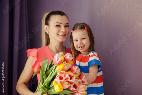 Happy mother's day! daughter congratulates mom and gives a bouquet of flowers to tulips. Happy children and parents, family.