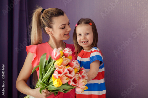 Happy mother's day! daughter congratulates mom and gives a bouquet of flowers to tulips. Happy children and parents, family.