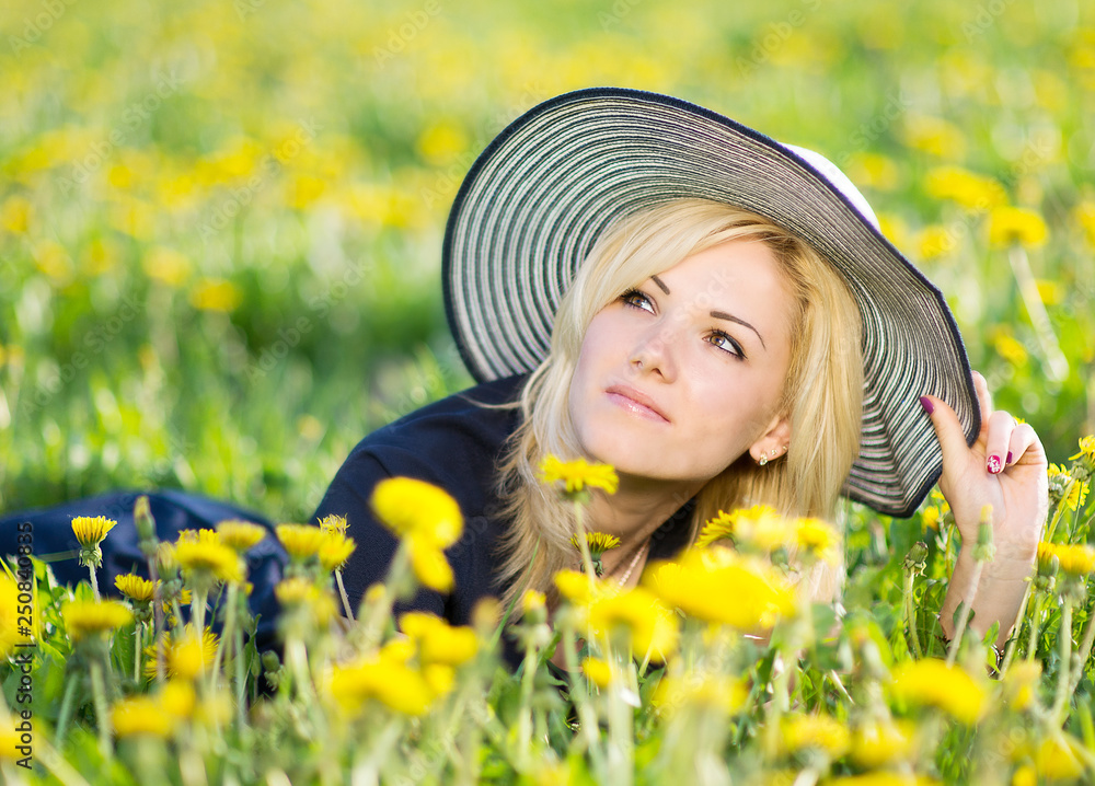 Image of pretty woman lying down on dandelions field, happy cheerful girl resting on dandelions meadow, relaxation outdoor in springtime, vacation 