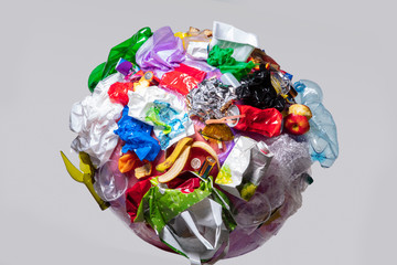 A globe of the earth with trash over white background, the concept of ecology problem and World Environment Day. Photo with message for social advertising, place for inscription