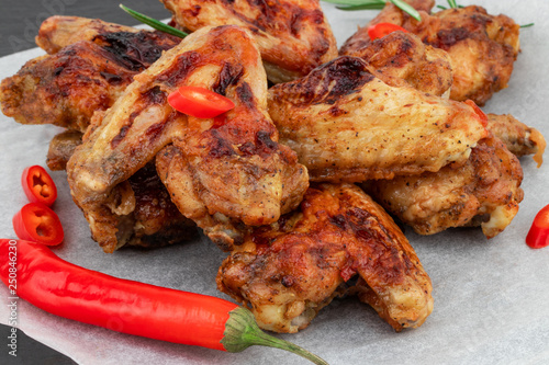 Baked chicken wings with and sweet chili sauce on  wooden board over dark background