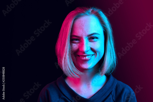 Happy business woman standing and smiling on neon studio background. Beautiful female half-length portrait. Young emotional woman. The human emotions, facial expression concept