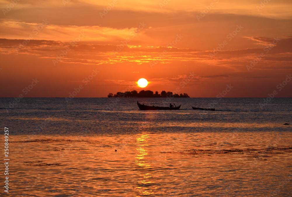 Sunset on the island with fishing boat silhouette