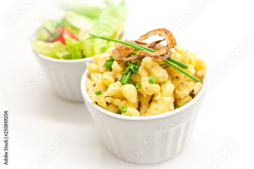 cheese spaetzle with roasted onions and parsley in a white bowl on white plate