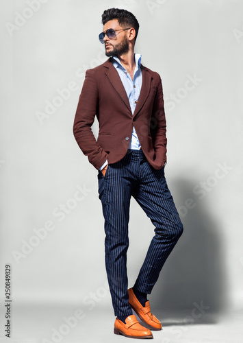 Elegant young handsome man in suite wearing glasses. Studio fashion portrait.
