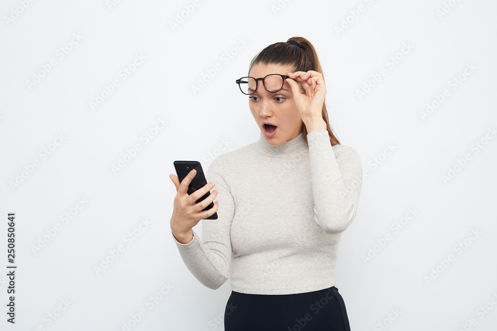 surprised young woman with mobile phone in hand and glasses surprised young woman with mobile phone in hand and glasses