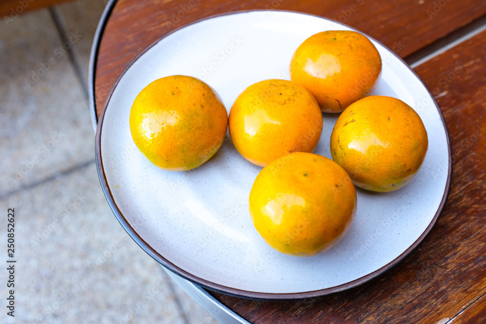 Oranges in white ceramic plate on wooden table Oranges in white ceramic plate on wooden table