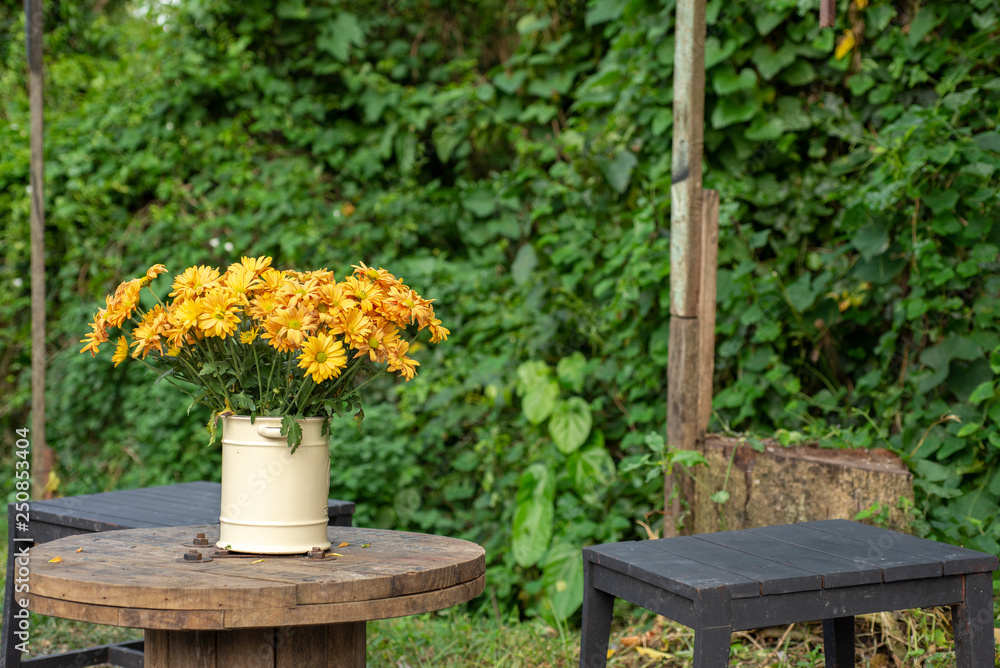 Outdoor yellow flower in vase on wood table Outdoor yellow flower in vase on wood table