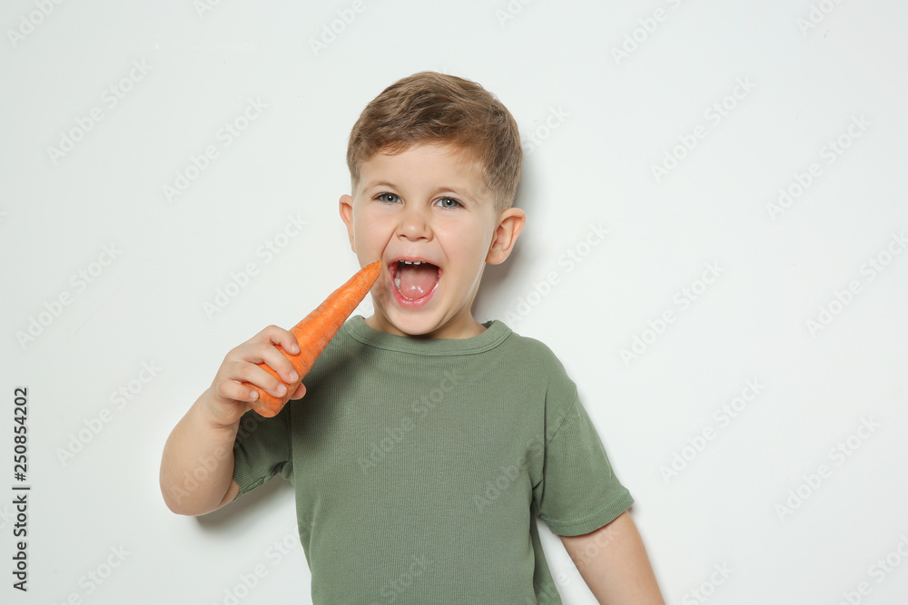 Adorable little boy eating carrot on white background. Space for text Adorable little boy eating carrot on white background. Space for text