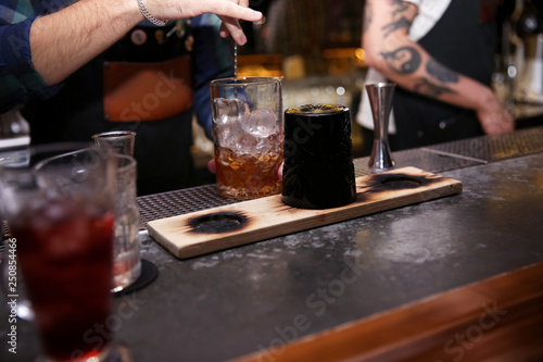Bartender preparing tasty cocktail at counter in nightclub  closeup