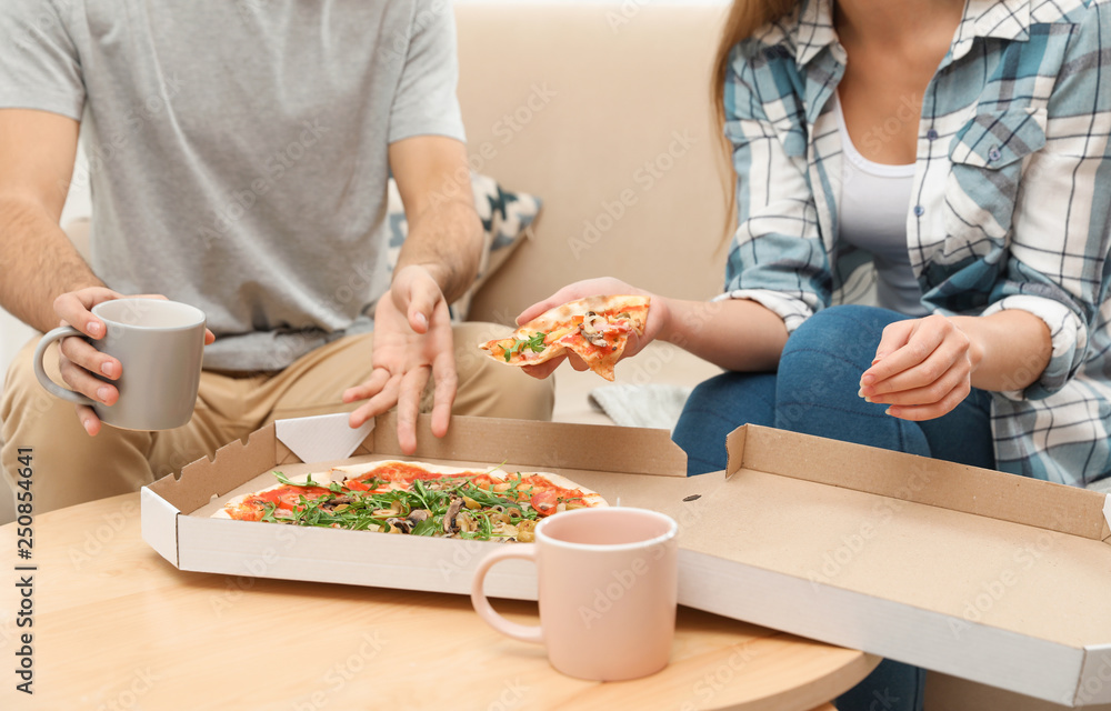 Young couple having pizza for lunch at home, closeup. Food delivery