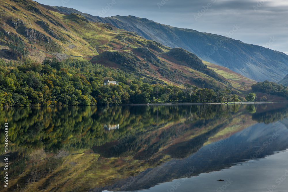 A perfectly still Lake Buttermere on a breathless day in the Lake District, reflecting the beautiful autumn colours which are starting to show in the trees.